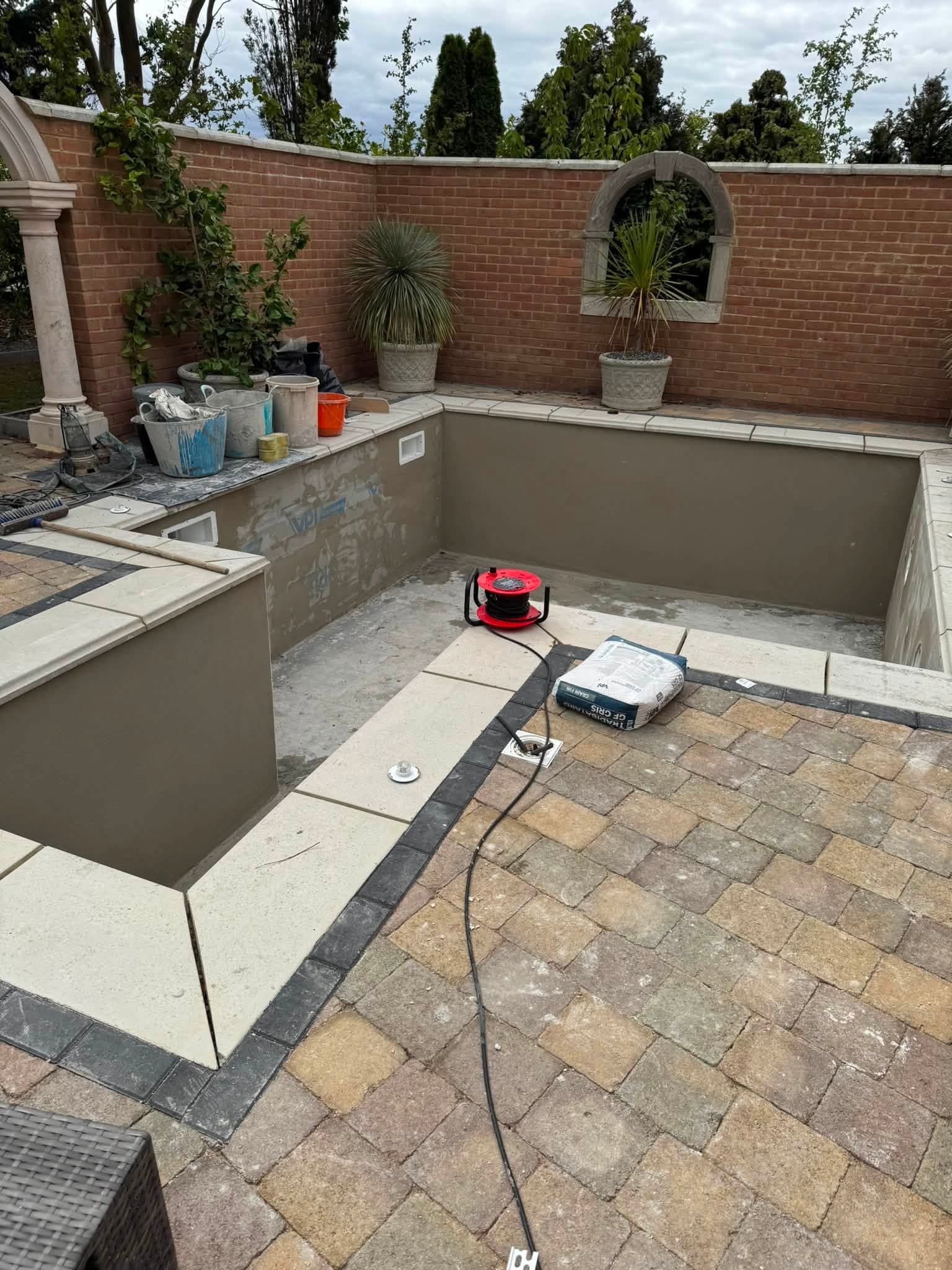Outdoor pool with rendered walls in a brick courtyard