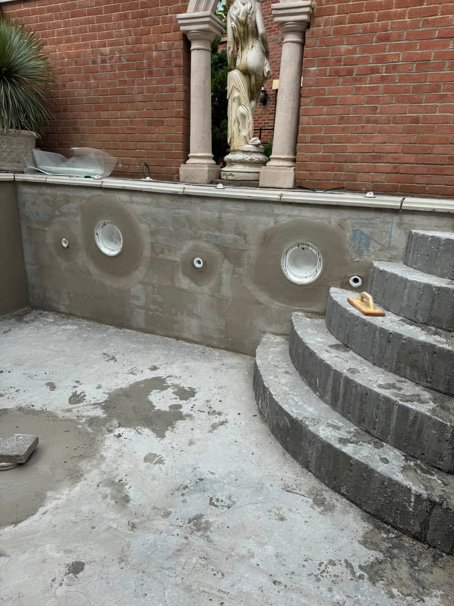 Pool wall being rendered, with a trowel on the steps